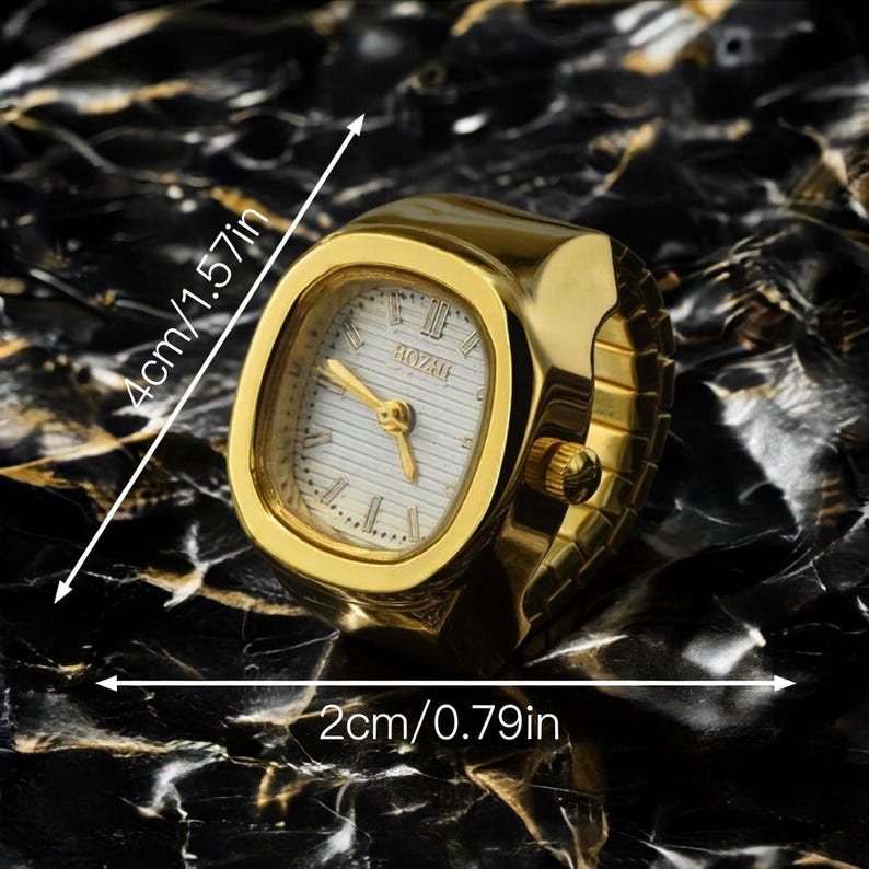 May include: A gold-toned ring watch with a rectangular face, measuring 4cm (1.57in) by 2cm (0.79in). The watch face is white with black Roman numerals and gold hands. The band is a flexible, expandable design.