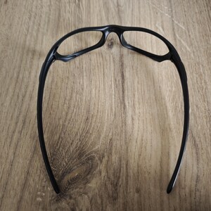 May include: Black sports glasses with a curved frame design. The glasses have a sleek, modern look, with a focus on functionality and a lightweight build. The lenses are not visible in this image.