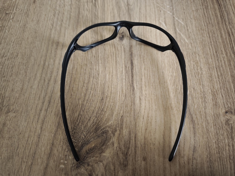 May include: Black sports glasses with a curved frame design. The glasses have a sleek, modern look, with a focus on functionality and a lightweight build. The lenses are not visible in this image.