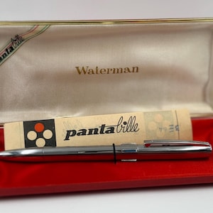 K&ouml;nnte beinhalten: Ein silberner Waterman-Stift in einer roten und goldenen Schatulle. Die offene Schatulle zeigt den Stift, einen Papiereinleger mit dem Text "panta bille" und das Wort "Waterman" auf dem Deckel.