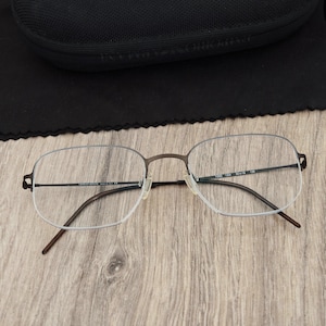 May include: Giorgio Armani eyeglasses featuring a dark brown metal frame with a semi-rimless design. The thin temples are dark brown, and the inner arm displays the text Giorgio Armani Made in Italy CE, with model details 1055 1304 50 16 135.