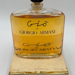 May include: A rectangular glass bottle of Giorgio Armani Gi&ograve; perfume. The bottle contains a golden-colored liquid and is topped with a gold-colored cap. The label reads "Gi&ograve; de Giorgio Armani". The box reads "100 mL" and "3.4 FL.OZ."