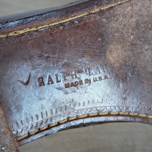 May include: Close-up of the sole of a brown leather shoe. The text "RALPH LAUREN MADE IN U.S.A." is visible. The stitching around the sole is a light tan color.