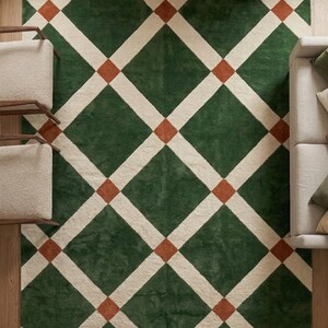 May include: A rectangular area rug featuring a geometric pattern of large dark green diamonds separated by thick cream-colored lines, with small burnt orange squares positioned at each intersection point of the grid across the entire surface.