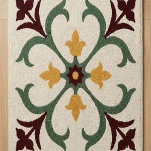 May include: A rectangular rug featuring a cream-colored base with a central floral motif. The design includes symmetrical green scrolling vines, four yellow petal-like shapes, and four dark red floral elements at the corners and center.