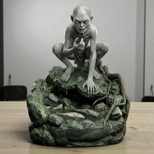 以下が含まれることがあります： 映画『ロード・オブ・ザ・リング』に登場するゴラムの灰色の彫刻。苔むした岩の上にしゃがみ、小さな池と魚がある。彫刻は詳細な特徴と不気味な表情をしている。