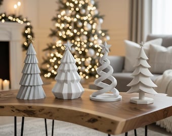 Puede incluir: Cuatro figuras decorativas de árboles de Navidad en varios diseños y tonos de blanco y gris sobre una mesa de centro de madera. Cada árbol está coronado con una estrella. Un árbol de Navidad con luces en el fondo.
