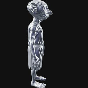 May include: A silver-colored figurine of a slender humanoid figure with a large nose and ears, wearing a tunic and skirt. The figure has a detailed face and is standing with its arms at its sides. The figurine is on a black background.