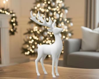May include: A white decorative reindeer figurine with large antlers stands on a wooden table. The reindeer is in front of a Christmas tree with glowing lights, creating a festive holiday scene.