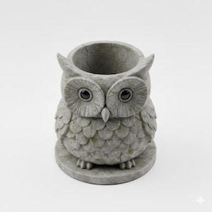 May include: A gray owl-shaped planter made of stone. The owl has large, round eyes and a textured surface. The planter has a circular opening at the top and is designed to hold small plants or flowers. The owl is sitting on a round base.