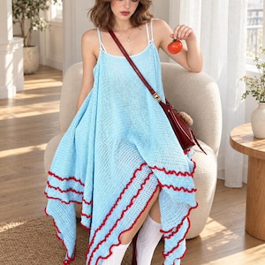 May include: A light blue crochet dress featuring thin spaghetti straps and a handkerchief hemline with a contrasting red ruffled trim. The garment is paired with white knee-high socks and dark red Mary Jane shoes, accessorised with a dark red crossbody bag.