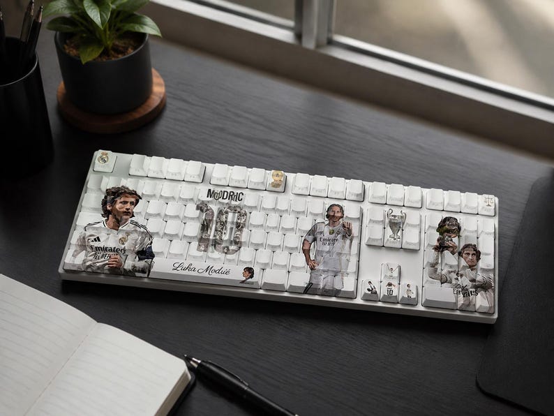 May include: A white mechanical keyboard featuring custom keycaps with printed graphics of Luka Modrić in a Real Madrid kit, the number 10, the text "MODRIC" and "Luka Modrić," and a Champions League trophy icon across several keys.