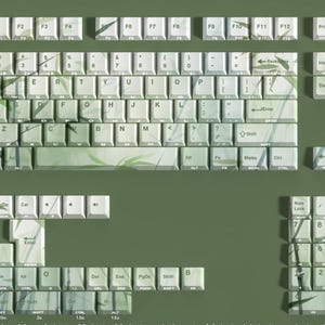 May include: A full set of keycaps in a light green color with a bamboo leaf design. The keycaps are for a mechanical keyboard, with a standard QWERTY layout and a number pad. The keycaps are made of a durable material.