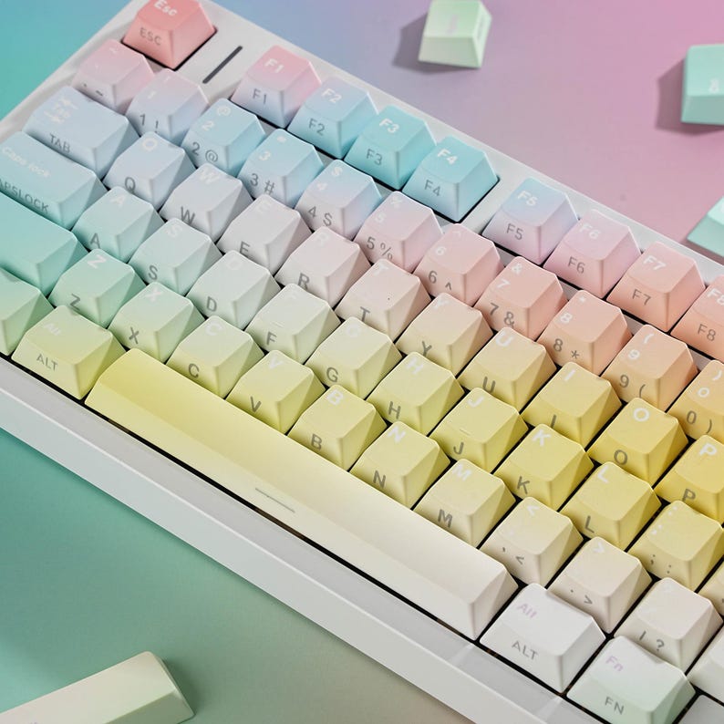 May include: A white mechanical keyboard with pastel-colored keycaps. The keys transition from yellow to pink, with function keys labeled F1 through F8. The keyboard has a compact layout, with an Esc key in the upper left corner.