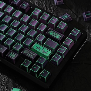 May include: A mechanical keyboard with purple keycaps featuring bright green edges and lettering. Several keys display Japanese characters and English text including "EVANGELION-09". The keycaps have a weathered, distressed appearance with visible wear marks on the edges, set against a black keyboard frame.