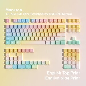 May include: A set of 131 Macaron-themed keycaps in a Cherry profile. The keycaps are in a gradient of pastel colors, including pink, yellow, blue, and green. The text "English Top Print" and "English Side Print" are visible.