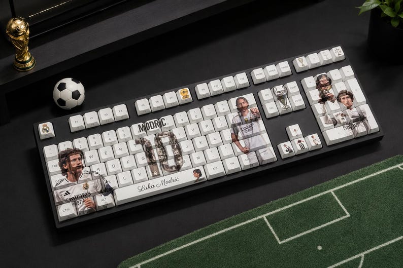 May include: A black mechanical keyboard with white keycaps featuring custom graphics of Luka Modrić, the number 10, and soccer-themed icons. The text "MODRIC" and "Luka Modrić" is printed on the keys, alongside images of the player in a white jersey.