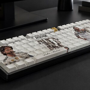 May include: A black computer keyboard with white keycaps featuring custom graphics of a soccer player. The keys display the name Luka Modrić in script, the text MODRIC in block letters, and multiple photographic images of the athlete in a white jersey.