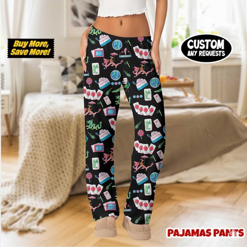 May include: Black pajama pants with a repeating pattern of Asian-themed illustrations in pink, blue, and green. The pants have a drawstring waist and the words "Custom Any Requests" are printed on the right leg. The words "Buy More, Save More!" are printed on the left leg.