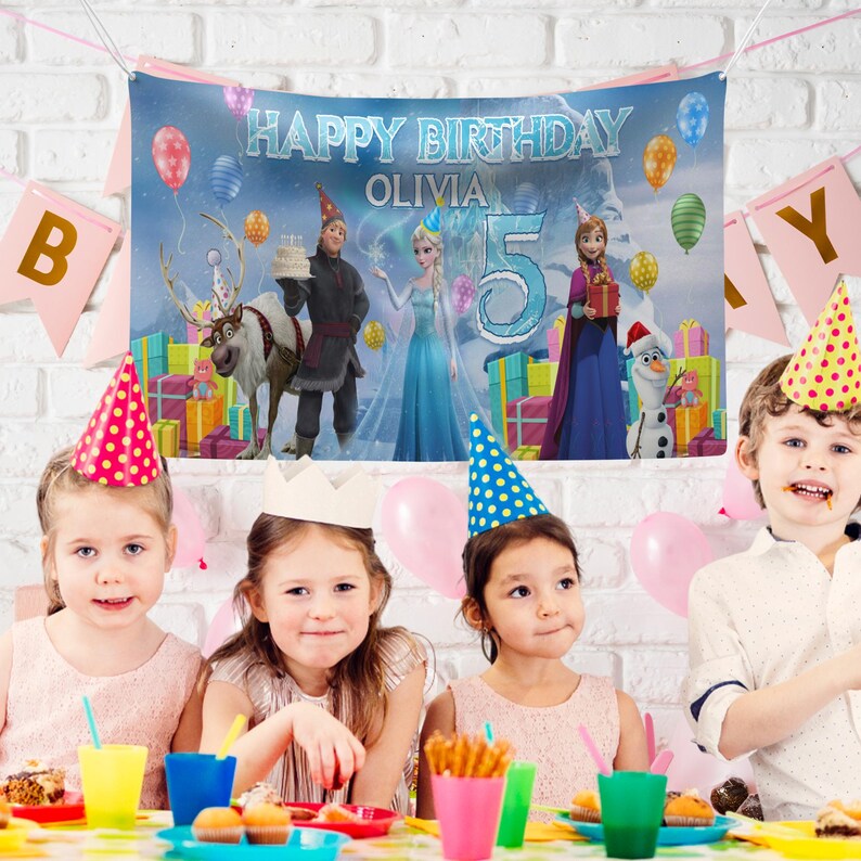 May include: A birthday party scene with a banner that reads "Happy Birthday Olivia 5". The banner features cartoon characters and balloons. Four children wearing party hats sit at a table with snacks and drinks. Pink and blue balloons are also present.