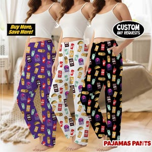 Puede incluir: Tres pares de pantalones de pijama en morado, blanco y negro, cada uno con gráficos temáticos de Taco Bell. El par morado tiene un fondo oscuro, el blanco un fondo claro y el negro un fondo oscuro. El texto incluye "Buy More, Save More!" y "Custom Any Requests".