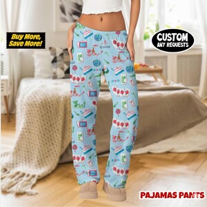 May include: Light blue pajama pants with a repeating pattern of playing cards, dragons, and other themed graphics. The text "CUSTOM ANY REQUESTS" is visible. The text "Buy More, Save More!" is also visible. The text "PAJAMAS PANTS" is visible.
