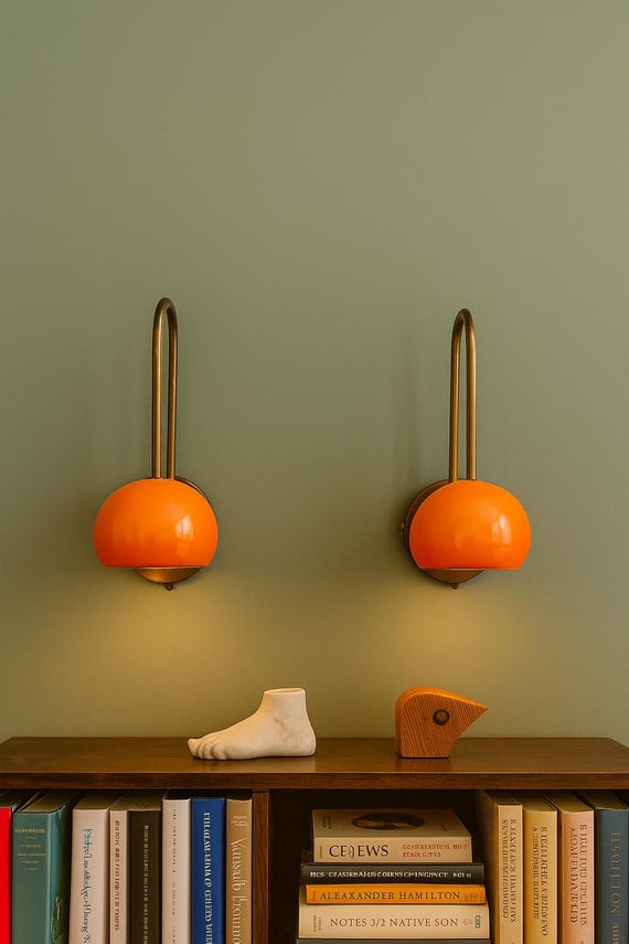 Bold mid-century brass sconces with vibrant orange dome shades for a retro modern statement.