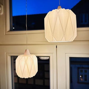 Könnte beinhalten: Ein Set aus drei Keramikbechern mit gesprenkelter, matter Oberfläche. Die Becher sind in den Farbtönen Creme, Hellgrau und Dunkelgrau gehalten. Jeder Becher hat ein schlichtes, minimalistisches Design, ideal für Kaffee oder Tee.