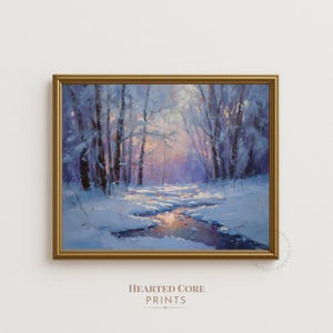 Könnte beinhalten: Gerahmtes Winterlandschaftsgemälde. Das Kunstwerk zeigt einen schneebedeckten Wald mit einem Bach, der das sanfte Licht der untergehenden Sonne reflektiert. Der Text "HEARTED CORE PRINTS" befindet sich unten.