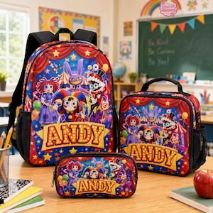 Op de afbeelding: Een set bestaande uit een rugzak, lunchtas en etui met een rood, blauw en geel circusontwerp, stripfiguren en de naam ANDY in een marquee-lettertype. Elk item is voorzien van zwarte randen, mesh zijvakken en ritssluitingen.