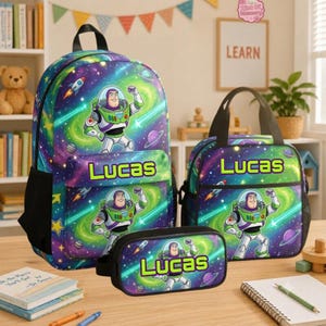 May include: A backpack, lunch bag, and pencil case set featuring a space-themed pattern with planets, stars, and the character Buzz Lightyear. Each item displays the name Lucas in bright green text against a purple and blue galaxy background.