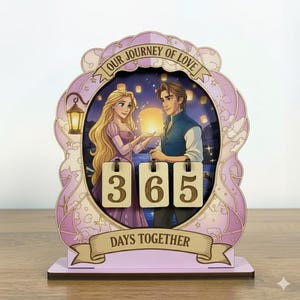 May include: A wooden decorative piece with a romantic theme. It features a couple from a fairytale, with the text "OUR JOURNEY OF LOVE" and "DAYS TOGETHER". The counter displays "365". The piece is in shades of pink, purple, and brown.