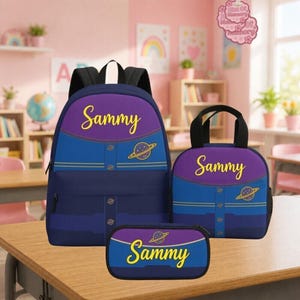 May include: A purple and blue backpack, lunch bag, and pencil case set featuring the name Sammy in yellow script and a small planet graphic. Each item has a dark blue lower section with horizontal lines and a purple upper section with black straps.