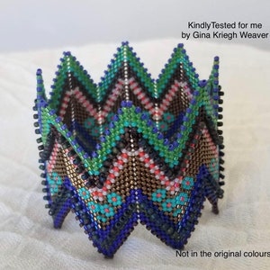 May include: A beaded, geometric, multi-coloured, folded, decorative piece. The piece is made of small, colourful beads in shades of blue, green, brown, pink, and orange. The piece is folded into a star shape. "Kindly Tested for me by Gina Krieg Weaver" and "Not in the original colours" are written in the image.