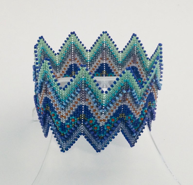 May include: A beaded bracelet with a zig-zag pattern in shades of blue, green, and brown.
