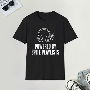 以下が含まれることがあります： 黒の半袖Tシャツで、ヘッドフォンと小さな稲妻のアイコンが白でプリントされています。ヘッドフォンの下には「POWERED BY SPITE PLAYLISTS」というテキストが、胸の中央にすっきりとした白いサンセリフ体で配置されています。
