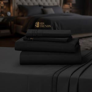 May include: A stack of black bed sheets, including a fitted sheet, flat sheet, and pillowcases. The sheets are neatly folded and displayed on a bed, with a matching comforter and pillows in the background. The bedding set is a solid, dark color.