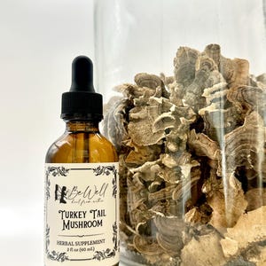 May include: A brown glass bottle with a black dropper and a label that reads "BeWell Turkey Tail Mushroom Herbal Supplement 2 fl oz (60 mL)". Beside it is a clear glass jar filled with dried turkey tail mushrooms.