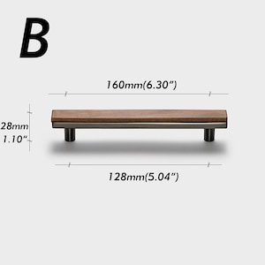 May include: A cabinet pull with a dark wood top and a silver-coloured base. The pull is 160mm long and 28mm high. The distance between the screw holes is 128mm. The letter "B" is in the upper left corner.
