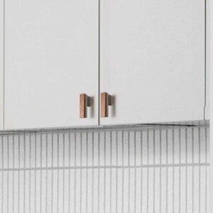 May include: Image of white kitchen cabinet doors with two pairs of copper-coloured rectangular cabinet pulls. The pulls are vertically aligned and have a simple, modern design. A white and grey tiled backsplash is in the background.