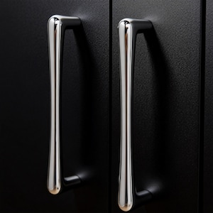 Può includere: Due maniglie per armadietti cromate lucide contro un'anta di armadio nera. Le maniglie sono orientate verticalmente, con una parte superiore e inferiore arrotondate e un design elegante e moderno. L'anta dell'armadio nera ha una superficie strutturata.