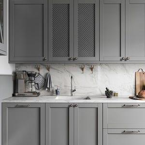 May include: A contemporary kitchen featuring grey cabinets and a marble worktop. The upper cabinets have a decorative mesh design. A coffee machine, sink, and chopping board are visible. The kitchen has a clean and minimalist aesthetic.