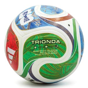 May include: A white soccer ball featuring multi-colored graphic panels in red, green, and blue with gold accents. The ball displays the text TRIONDA, FIFA logo, and the words BALON OFFICIAL DEL PARTIDO, OFFICIAL MATCH BALL, BALLON DE MATCH OFFICIAL.