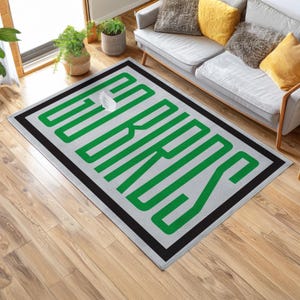 以下が含まれることがあります： 明るい灰色の背景に、緑色の「SERIOUS」という文字が大胆にデザインされた長方形のラグ。 文字は黒で縁取られ、ラグには黒い縁取りがあります。 ラグの上には白い物体があります。 屋内用です。