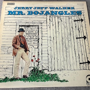 May include: Vintage vinyl record album cover for Jerry Jeff Walker's "Mr. Bojangles." The cover features a cartoon illustration of a man in front of a wooden structure. The album title and artist's name are in blue text. The ATCO logo is in the lower right corner.
