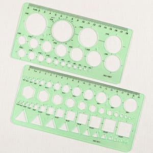 May include: Two light green plastic drafting templates featuring various geometric cutouts. The top template, labeled NO.1807, includes circular shapes. The bottom template, labeled NO.1811, features circles, hexagons, squares, and triangles with metric rulers.