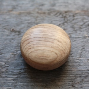 Puede incluir: Un pomo redondo de madera de color marr&oacute;n claro con un patr&oacute;n de veta de madera.