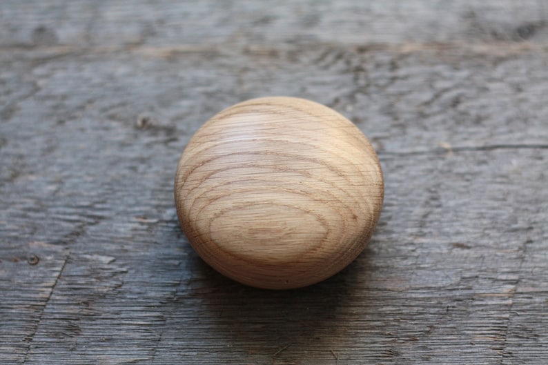 Puede incluir: Un pomo redondo de madera de color marr&oacute;n claro con un patr&oacute;n de veta de madera.