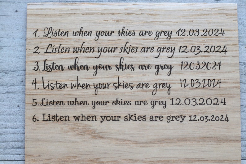 May include: A wooden sign with the text "Listen when your skies are grey" repeated six times, each with a different date: 12.08.2024, 12.03.2024, 12.032024, 12.03.2024, 12.03.2024, and 12.03.2024.