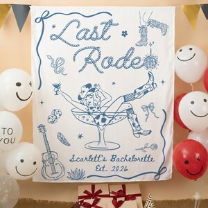 May include: White fabric banner with a blue illustration. The banner reads "Last Rode" in rope-style lettering, with a cowgirl in a martini glass. Additional illustrations include a guitar, dice, and boots. The text "Scarlett's Bachelorette Est. 2026" is also present.